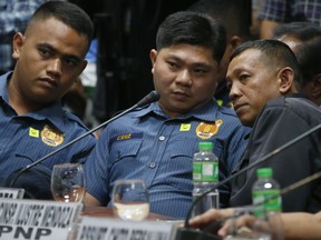 In this Aug. 24, 2017, file photo, from left; police officers Jeremias Pereda, Jerwin Cruz and Arnel Oares talk during a senate hearing on the killing of Kian Loyd Delos Santos, a 17-year-old Grade 11 student, allegedly during a drug crackdown in Manila, Philippines.