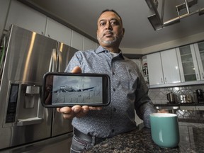 Invor Bedessee stands in his home on Nov. 12 holding an iPhone image of the Fly Jamaica flight that crash-landed in Guyana three days earlier. The photo of the plane was taken by Denis Chabral for AFP / Getty Images.