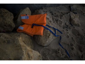 A life vest lies on the rocks near the village of Canos de Meca in southern Spain, Tuesday, Nov. 6 2018. Spain's maritime rescue service says at least 17 people have died trying to reach Spanish territory in boats departing from North Africa but rescued 80 people Monday from two boats and recovered the bodies of 13 dead migrants in the Alboran Sea, part of the western Mediterranean route into Europe. In a separate incident, the Spanish Civil Guard says it found four bodies of migrants and 22 survivors, all men from northern Africa, after their wooden dinghy hit a reef.