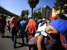 A sleeping Honduran girl is carried as a group of Central American migrants, representing the thousands participating in a caravan trying to reach the U.S. border, undertake an hours-long march to the office of the United Nations' humans rights body in Mexico City, Thursday, Nov. 8, 2018. Members of the caravan which has stopped in Mexico City demanded buses Thursday to take them to the U.S. border, saying it tis too cold and dangerous to continue walking and hitchhiking.