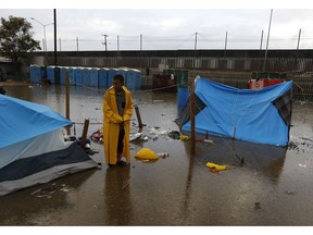 A boy examines a flooded tent between bouts of heavy rain at a sports complex sheltering thousands of Central Americans in Tijuana, Mexico, Thursday, Nov. 29, 2018. Aid workers and humanitarian organizations expressed concerns Thursday about the unsanitary conditions at the sports complex in Tijuana where more than 6,000 Central American migrants are packed into a space adequate for half that many people and where lice infestations and respiratory infections are rampant.