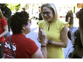 A supporter crosses her fingers as she talks with Democratic U.S. Senate candidate Kyrsten Sinema, at a get-out-the-vote event at the Arizona Education Association headquarters in Phoenix,  Saturday, Nov. 3, 2018. Sinema is facing Republican Martha McSally in the race to replace Republican Sen. Jeff Flake, who is retiring.