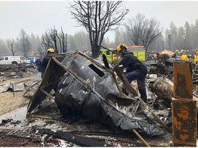 Steven McKnight, right, and Daniel Hansen saw through large pieces of sheet metal so they can be moved to allow cadaver dogs to search beneath them for signs of human remains at a mobile home park in Paradise, Calif., Friday, Nov. 23, 2018. They said the mobile home park had already been hand searched, so they were re-examining it with search dogs.