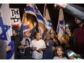 Israeli protesters hold flags during a demonstration against the cease-fire between Israel and Gaza's Hamas in the southern Israeli city of Ashkelon, Wednesday, Nov. 14, 2018. Israel's defense minister on Wednesday abruptly resigned to protest a new cease-fire with Hamas militants in Gaza, throwing the government into turmoil and pushing the country toward an early election.