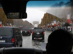 As seen from inside the press vehicle, the motorcade of President Donald Trump drives up the Champs Elysees to an Armistice Day Centennial Commemoration at the Arc de Triomphe, Sunday Nov. 11, 2018, in Paris. As he was arriving, at least one woman ran out toward the presidential motorcade with slogans -- including the word FAKE -- written on her chest. The woman was stopped by police and the motorcade continued uninterrupted.
