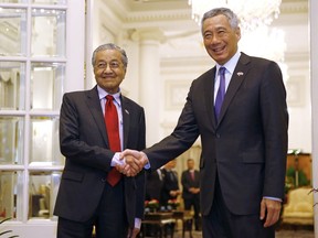 Malaysia's Prime Minister Mahathir Mohamad, left, shakes hands with Singapore's Prime Minister Lee Hsien Loong at the Istana in Singapore, Monday, Nov. 12, 2018.