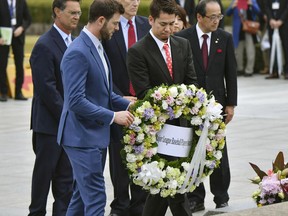 Mitch Haniger of the Seattle Mariners, front left, Kenta Maeda, of the Los Angeles Dodgers, front right, with manager Don Mattingly, rear left, lay a wreath at the cenotaph in the Peace Memorial Park which commemorates the victims of the atomic bombings in 1945, in Hiroshima, western Japan, Monday, Nov. 12, 2018. (Kyodo News via AP)