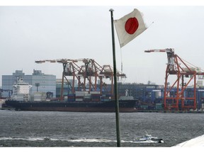 In this Aug. 24, 2018, photo, a Japanese flag is hoisted near the pier of a container terminal in Tokyo. Japan recorded a trade deficit in October but a recovery in exports after getting slammed by natural disasters in September, according to government data released Monday, Nov. 19, 2018. Exports grew 8.2 percent from the same month the previous year, the Finance Ministry said.