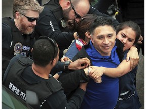 In this April 3, 2018 photo, Memphis police arrest Spanish-language reporter Manuel Duran during an immigration protest in Memphis, Tenn.  Duran, who faces deportation after his arrest while covering the protest in Tennessee said Tuesday, Nov. 13 he was unjustly detained and faces danger if sent back to El Salvador. Duran spoke publicly about his case for the first time since his arrest at the April rally protesting immigration policies the day before the 50th anniversary of the assassination of civil rights leader Martin Luther King Jr. in downtown Memphis.