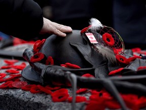 A man touches the helmet on the Tomb of the Unknown Soldier after laying a poppy following the national Remembrance Day ceremony at the National War Memorial in Ottawa on Nov. 11, 2017.