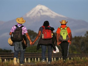 In this Nov. 5, 2018 photo, Central American migrants begin their morning trek facing Pico de Orizaba volcano as part of a thousands-strong caravan hoping to reach the U.S. border, upon departure from Cordoba, Veracruz state, Mexico. A big group of Central Americans pushed on toward Mexico City from a coastal state Monday, planning to exit a part of the country that has long been treacherous for migrants seeking to get to the United States.