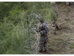 Members of the U.S.military place razor wire along the U.S.-Mexico border near the McAllen-Hidalgo International Bridge, Friday, Nov. 2, 2018, in McAllen, Texas.
