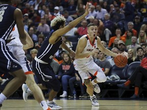 Virginia guard Kyle Guy (5) turns the corner past George Washington's Justin Mazzulla (0) in the first half of an NCAA college basketball game Sunday, Nov. 11, 2018, in Charlottesville, Va.
