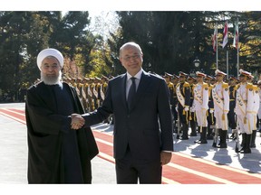 In this photo released by official website of the Office of the Iranian Presidency, Iraqi President Barham Salih, right, and his Iranian counterpart Hassan Rouhani shake hands during an official welcome ceremony for Salih at the Saadabad Palace in Tehran, Iran, Saturday, Nov. 17, 2018. Salih is visiting Iran less than two weeks after the United States restored oil sanctions that had been lifted under the 2015 nuclear deal. (Iranian Presidency Office via AP)