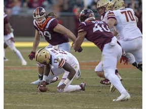 Boston College Anthony Brown quarterback spins and drops a knee under pressure from Virginia Tech's Vinny Mihota, 99, and Emmanuel Belmar, 40,  during the first half of an NCAA college football game in Blacksburg, Va., Saturday, Nov. 3, 2018.