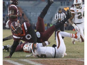 Miami quarterback N'Kosi Perry (5) scores on a one yard run as Virginia Tech defender Khalil Ladler (9) falls on top of him in the end zone in the first half of an NCAA college football game in Blacksburg Va., Saturday, Nov. 17 2018.