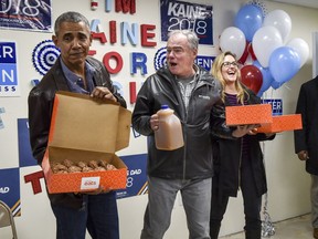 Former President Barack Obama, left, carrying donuts, with Sen. Tim Kaine, centre, and House of Representatives candidate Jennifer Wexton, right, for a rally with campaign volunteers, on Nov. 5, 2018 in Fairfax, Va.