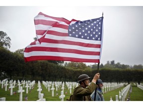 FILE In this Sunday, Sept. 23, 2018 file photo, re-enactors in World War I military uniforms carry an American flag in the Meuse-Argonne cemetery, northeastern France. After the United States declared war on Germany in April 1917, its standing army of 127,500 became an armed force of 2 million within 1 ½ years. On Nov 11, 1918, allies like Britain and France were exhausted, Germany was as good as defeated and U.S. Gen. John J. Pershing had another 2 million troops ready to come over.