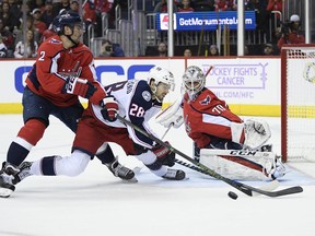 Columbus Blue Jackets right wing Oliver Bjorkstrand (28), of Denmark, battles for the puck against Washington Capitals defenseman Matt Niskanen (2) and goaltender Braden Holtby (70) during the first period of an NHL hockey game, Friday, Nov. 9, 2018, in Washington.