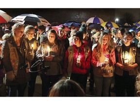 Girl Scouts sing as hundreds of community members turn out in the rain Sunday evening, Nov. 4, 2018, for a candlelight vigil at Halmstad Elementary School in Chippewa Falls, Wis., in remembrance of three fourth grade Girl Scouts and a parent who died Saturday, after being struck by a pickup truck while their troop was picking up trash along a rural highway. The 21-year-old driver, Colten Treu of Chippewa Falls, sped off but later surrendered. He will be charged with four counts of homicide, Lake Hallie police Sgt. Daniel Sokup said.