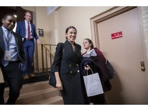 FILE - In this Nov. 15, 2018, file photo, Rep.-elect Alexandria Ocasio-Cortez, D-N.Y., joined at left by Rep.-elect Joe Neguse, D-Colo., exit a Democratic Caucus meeting in the basement of the Capitol in Washington. Ocasio-Cortez seems to be everywhere. She's cooked soup, live on Instagram. She's done laundry in public. And she's clapped back at critics of her clothing and a misstatement. The New York Democrat, who at 29 is the youngest woman to be elected to Congress, says she's documenting her journey to Capitol Hill to lift some of the mystery of the place and make it, 'real.'