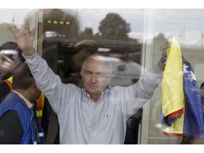 FILE - In this Nov. 17, 2017 file photo, holding a national Venezuelan flag, ousted Caracas Mayor Antonio Ledezma waves from inside El Dorado international airport, as he prepares for departure, in Bogota, Colombia. Now in exile Ledezma is taking his fight against Venezuela's socialist government abroad after he escaped house arrest in Caracas, and fled to Colombia.