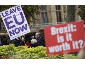 Pro and anti Brexit protesters hold placards as they vie for media attention near Parliament in London, Friday, Nov. 16, 2018.  Britain's Prime Minister May still faces the threat of a no-confidence vote, after several Conservative Party lawmakers said they had written letters asking for one.