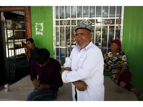 In this Sept. 21, 2018, photo, Muzitohtahon, center, a Uighur farmer in his early seventies who moved to the village three years ago, said he is no longer a Muslim, stands outside a convenience store at the Unity New Village in Hotan, in western China's Xinjiang region. While thousands of Uighur Muslims across China's Xinjiang region are forced into re-education camps, China's fledgling vision for ethnic unity is taking shape in a village where Han Chinese work and live alongside Uighur minorities.