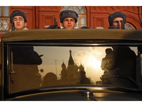 Russian soldiers dressed in Red Army World War II uniforms sit in the back of a truck as the St. Basil's Cathedral is reflected in the windshield prior to the start of the Nov. 7 parade in Red Square, with St. Basil Cathedral and thew Spasskaya Tower in the background, in Moscow, Russia, Wednesday, Nov. 7, 2018. The event marked the 77th anniversary of a World War II historic parade in Red Square and honored the participants in the Nov. 7, 1941 parade who headed directly to the front lines to defend Moscow from the Nazi forces.