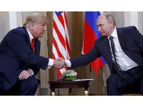 FILE- In this file photo taken on Monday, July 16, 2018, U.S. President Donald Trump, left, and Russian President Vladimir Putin, shake hands at the beginning of a meeting at the Presidential Palace in Helsinki, Finland.  The Kremlin said Wednesday Nov. 28, 2018, it still expects a meeting between President Vladimir Putin and President Donald Trump to go ahead as planned despite a suggestion from Trump that it could be canceled.