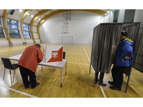 People check voting lists during the second round of the local elections in at a voting station in Lomianki, Poland, Sunday, Nov. 4, 2018. in local runoff elections to choose the mayors of several key cities, including Krakow and Gdansk, and more than 640 other towns and smaller localities.