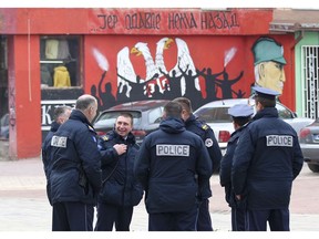 Police officers stand by the graffiti that shows Serbian coat of arms and silhouettes of people, reading: "... because there's no turning back", in northern Serb-dominated part of ethnically divided town of Mitrovica, Kosovo, Friday, Nov. 23, 2018. Kosovo police arrested three ethnic Serbs, including two police officers, early Friday on suspicion of involvement in the killing of a leading Serb politician in the north of the country.