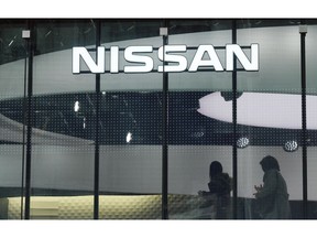 Visitors walk near the logo of Nissan at a Nissan showroom in Tokyo Thursday, Nov. 22, 2018. The arrest of Nissan chairman Carlos Ghosn could extinguish any remaining hopes for a merger with key shareholder Renault, which the Japanese company's CEO has publicly opposed.