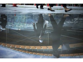 The process of raising the main roof of the Olympic Gymnastic Centre for Tokyo 2020 Olympic and Paralympic games currently under construction is reflected on a puddle in Tokyo Wednesday, Nov. 7, 2018. The new Tokyo 2020 Olympic venue is halfway completed. On Wednesday engineers raised a massive wooden roof section, one of five sections that will top out the 20.5 billion yen ($180 million) building.