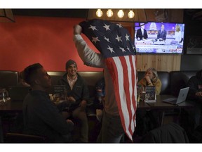 Sam Derrick from Minnesota celebrates with a United States flag during a gathering organized by Democrats Abroad in Beijing, China, Wednesday, Nov. 7, 2018. Democrats were poised to seize the House majority from President Donald Trump's Republican Party on Tuesday in a suburban revolt that threatened what's left of the president's governing agenda.