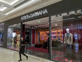 A woman walks out of an outlet of Dolce & Gabbana in Shanghai, China Wednesday Nov. 21, 2018. Dolce & Gabbana apologized Wednesday for insulting remarks about China it allegedly made in conversations on Instagram but denied that it was responsible, claiming its accounts had been hacked. (Chinatopix Via AP) CHINA OUT
