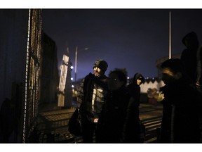 Honduran migrants stand at the border wall in Tijuana, Mexico, Friday, Nov. 30, 2018, before crossing over. The group was detained by U.S. Border Patrol agents as soon as they stepped onto U.S. territory. Thousands of migrants who traveled via a caravan members want to seek asylum in the U.S. but may have to wait months because the U.S. government only processes about 100 of those cases a day at the San Ysidro border crossing in San Diego.