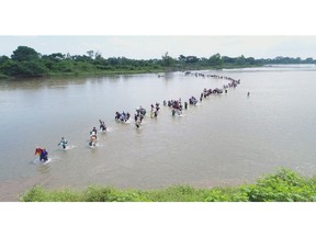 Salvadoran migrants cross the Suchiate river, the border between Guatemala and Mexico, on Friday, Nov. 2, 2018. A new group of Central American migrants has started on its way North with the stated purpose to make to the United States. The third caravan tried to cross the bridge between Guatemala and Mexico, but Mexican authorities told them they would have to show passports and visas and enter in groups of 50 for processing. The Salvadorans expressed misgivings that they would be deported, so they turned around and waded across a shallow stretch of the river to enter Mexico.