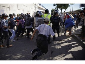 Migrants break past a line of police as they run toward the Chaparral border crossing in Tijuana, Mexico, Sunday, Nov. 25, 2018, near the San Ysidro entry point into the U.S. More than 5,000 migrants are camped in and around a sports complex in Tijuana after making their way through Mexico in recent weeks via caravan.