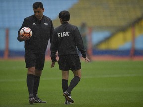 Referee Roberto Tobar, of Chile, inspects the Alberto Armando stadium in Buenos Aires, Argentina Saturday, Nov. 10, 2018. The South American Football Confederation, CONMEBOL, postponed, due to heavy rain, the Copa Libertadores first leg semifinal soccer match between Boca Junior and River Plate.