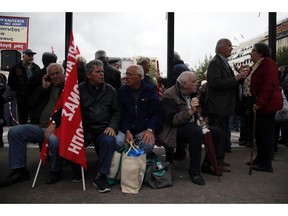 Elderly people sit on a bench during a rally in Athens, Tuesday, Nov. 20, 2018. Hundreds of pensioners protested demanding a return of funds lost as part of austerity measures.
