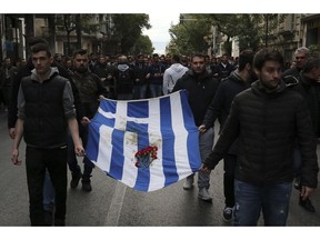 University students hold a blood-stained Greek flag from the deadly 1973 student uprising, in Athens, Saturday, Nov. 17, 2018. Several thousand people are expecting to march to the U.S. Embassy in Athens under tight police security to commemorate a 1973 student uprising that was crushed by Greece's military junta, that ruled the country from 1967-74.