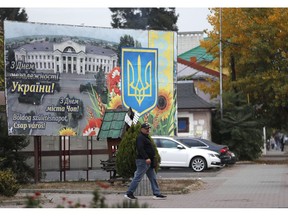 In this Thursday, Oct. 18, 2018 photograph, a man passes by a poster saying "Happy birthday, Chop city!" in Ukrainian, Russian and Hungarian, in Chop, Ukraine. A new education law that could practically eliminate the use of Hungarian and other minority languages in schools after the 4th grade is just one of several issues threatening this community of 120,000 people. Many are worried that even as Ukraine strives to bring its laws and practices closer to European Union standards, its policies for minorities seem to be heading in a far more restrictive direction.