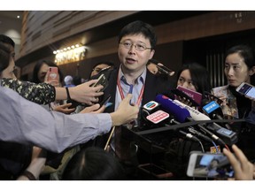 Feng Zhang, center, an institute member of Harvard and MIT's Broad Institute, reacts to reporters on the issue of world's first genetically edited babies after the Human Genome Editing Conference in Hong Kong, Tuesday, Nov. 27, 2018.