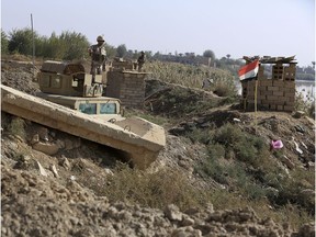 In this Tuesday, Nov. 13 2018 photo, Iraqi soldiers stand on the Iraqi side of the border with Syria, in the town of Qaim, Anbar province, Iraq. Life in Qaim has been put on hold as just across the border in Syria, fighting rages against one of the last major enclaves of the Islamic State group.