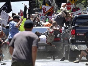 In this Aug. 12, 2017, file photo, people fly into the air as a vehicle is driven into a group of protesters demonstrating against a white nationalist rally in Charlottesville, Va.