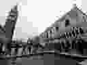 People walk on bridges set up in a flooded St Mark's square during 