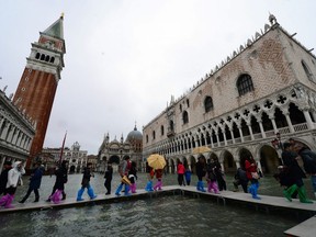 People walk on bridges set up in a flooded St Mark's square during "acqua alta" (high water) on November 1, 2012 in Venice.