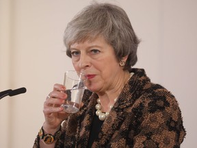 Britain's Prime Minister Theresa May drinks during a press conference on December 14, 2018 in Brussels during the second day of a European Summit aimed at discussing the Brexit deal.