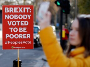 A tourist takes a photograph of the Houses of Parliament, near an anti-Brexit campaigner's placard, in central London on December 17, 2018.